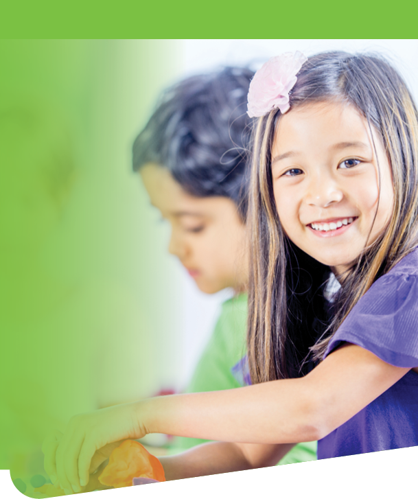 A multi ethnic group of little children sitting at a desk, in a school setting, studying or doing arts and crafts 